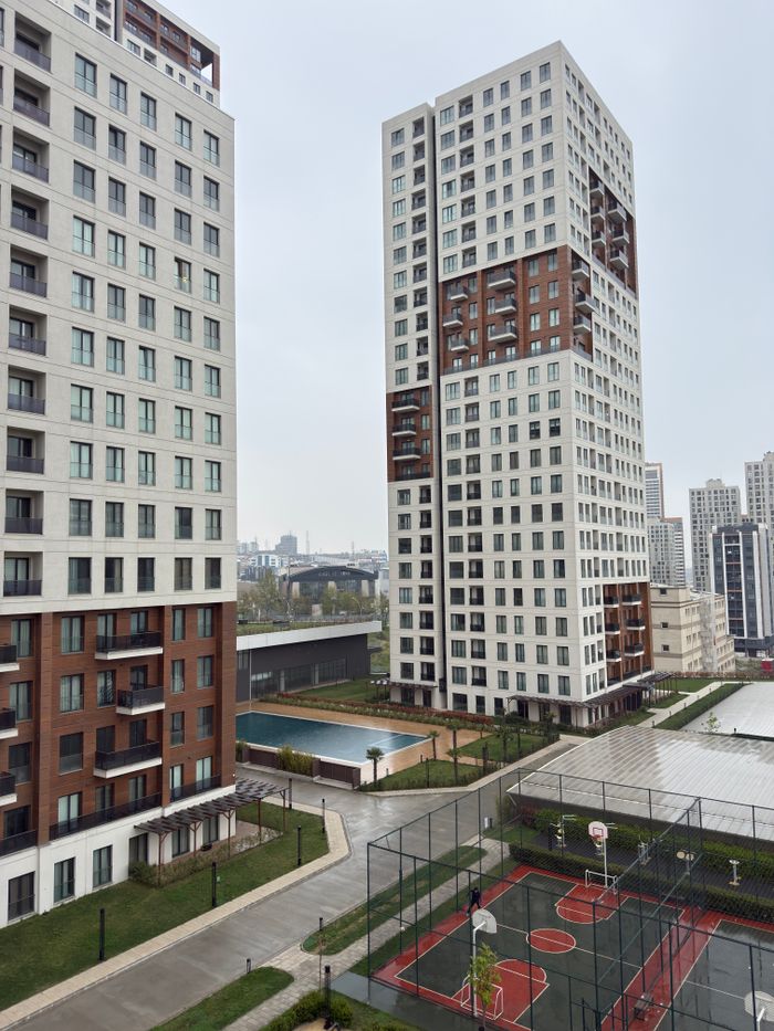mission-img Modern high-rise buildings with basketball courts and pool in urban residential area.
