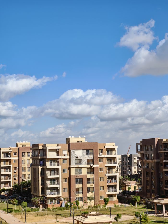 home-services-004 Contemporary apartment complex with bright blue sky and clouds.